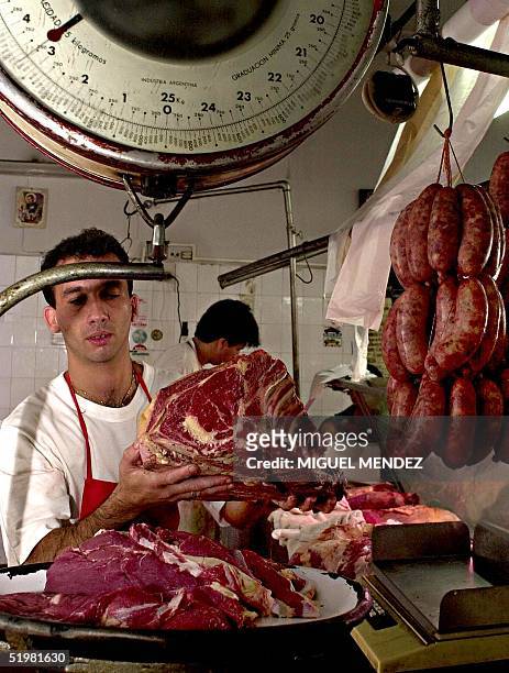 This photo, taken 23 February 2001, shows an employee of a butcher shop in Buenos Aires, Argentina, weighing immunized meat. Fotografia tomada el 23...