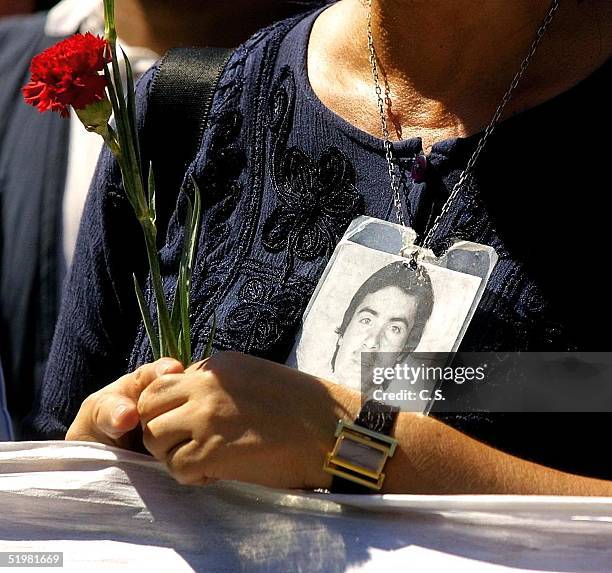 Woman holds a flower and the photo of a disappeared relative, during a march organized by human rights organizations in the region of Barriga, where...