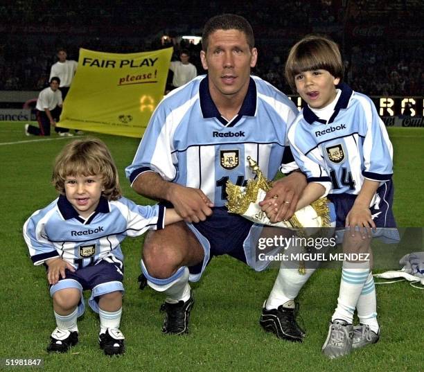 Diego Simeone pauses with his children Giovanni and Gianluca after he received a silver plate for playing 100 matches for Argentina in the Monumental...