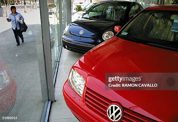 A woman passes in front of a dealer's showroom for, News Photo