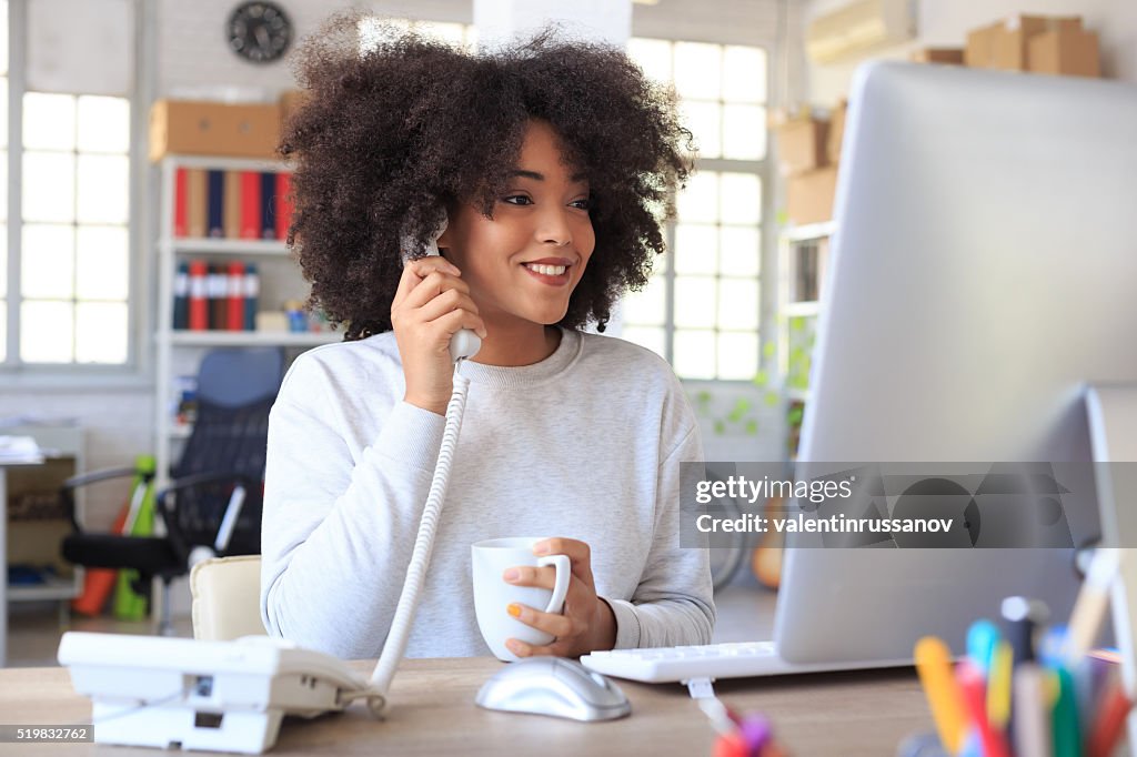 Sonriente mujer de negocios hablando en el teléfono con cable