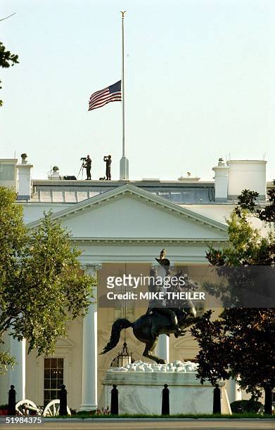 Secret Service agents take up position beneath the national flag at half mast atop the White House 11 September 2001 in Washington, DC, following...