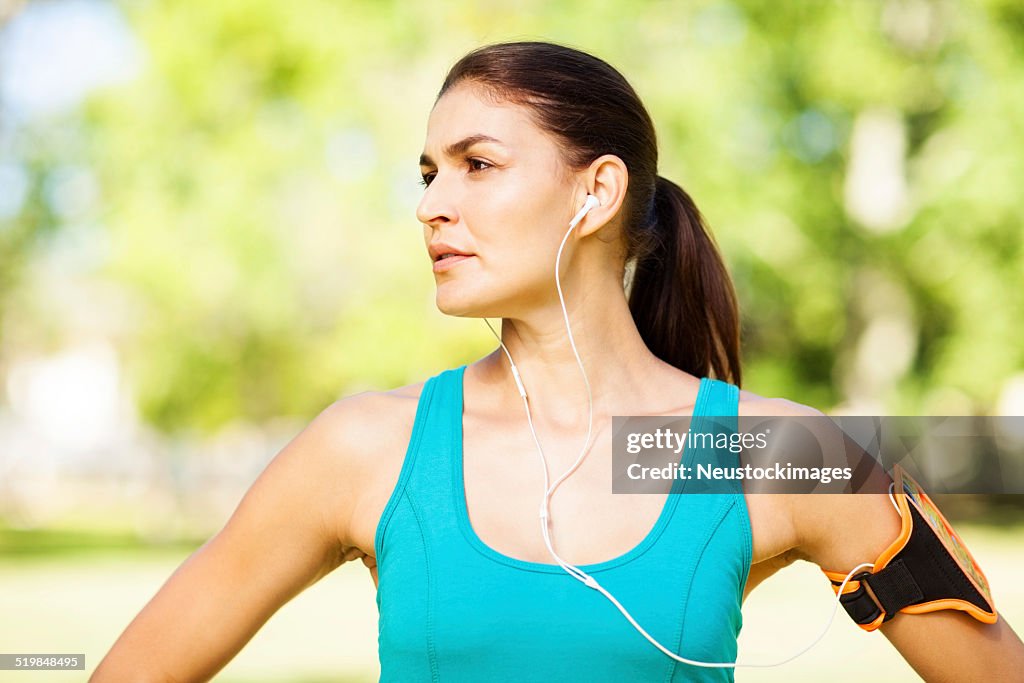 Sportiva donna ascoltando musica In auricolari nel parco