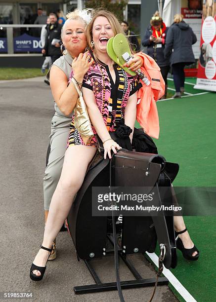 Racegoers ride on a horse racing simulator as they attend day 2 'Ladies Day' of the Crabbie's Grand National Festival at Aintree Racecourse on April...