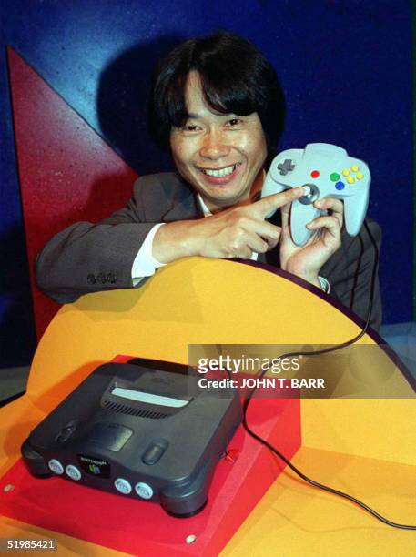 Video game designer, Shigeru Miyamoto from Japan, points to the handset of the new Nintendo 64 flagship game, Super Mario 64, at the Los Angeles...