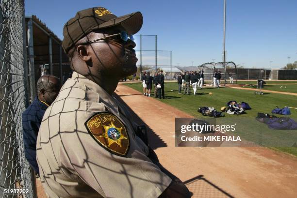 Pima County Deputy Sheriff Rodney Hamilton watches as the Arizona Diamondbacks take batting practice at their spring training facility 19 February...