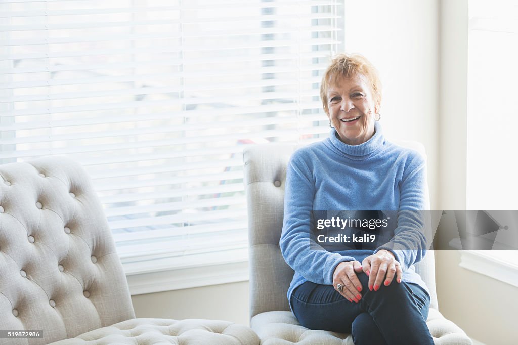 Senior woman sitting on chair by window