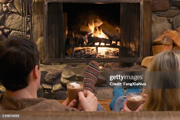 couple relaxing by a fire - log cabin fire stock pictures, royalty-free photos & images