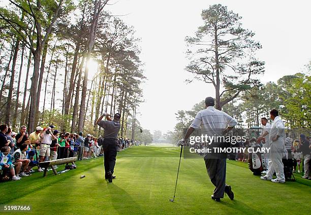 Former Masters champion Mark O'Meara of the US tees off on the seventh hole as 2001 defending champion Tiger Woods of the US watches 09 April, 2002...