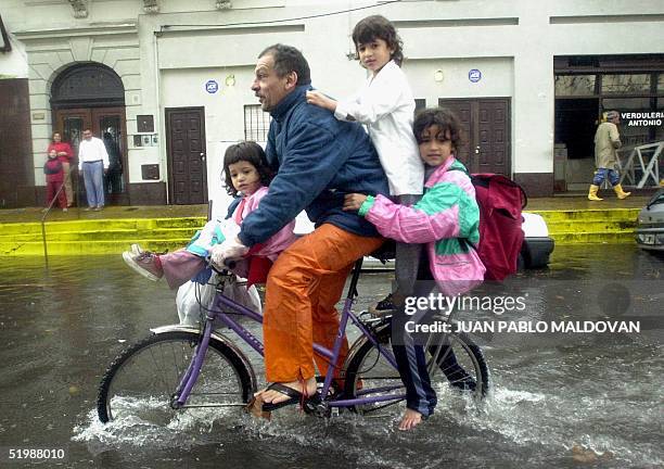 Man rides with his children through flooded streets in Buenos Aires, Argentina 13 May 2002. Un hombre carga en su bicicleta a sus tres hijas al salir...