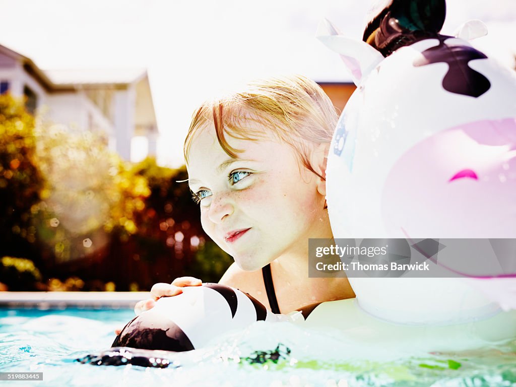 Smiling young girl swimming in backyard pool