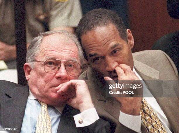 Simpson whispers to Defense attorney F. Lee Bailey during testimony of FBI special agent William Bodziak 19 June during the O.J. Simpson murder trial...