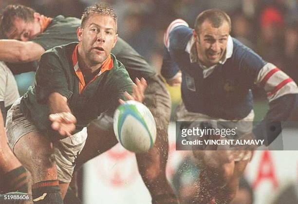 South Africa's Johan Roux gets the ball out of a scrum as French center Philippe Saint-Andre rushes to intercept during their World Cup semi-final...
