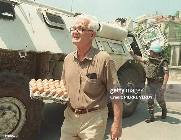 Sarajevan carrying eggs crosses "sniper alley" shielded by a UN APC 15 June. Heavy fighting has broken out 15 June north of the Bosnian capital,...