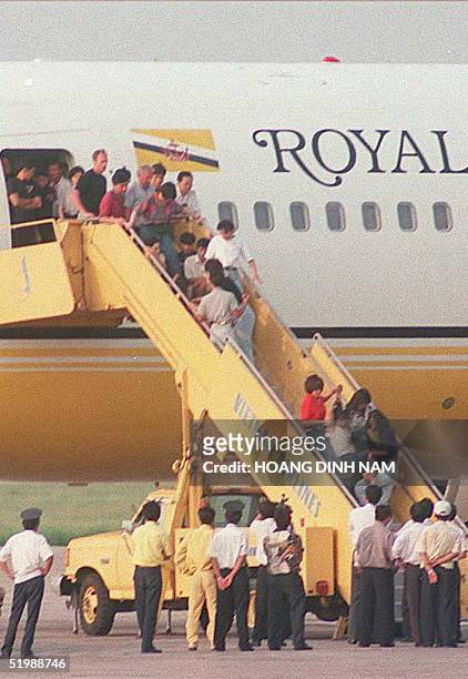 Woman is carried off while others sit on the gangway refusing to leave the airplane that brought a group of 100 deported Vietnamese boat people back...