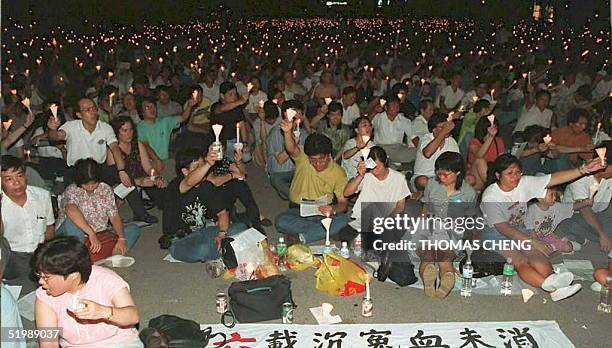 People sit during a candlelight vigil in Victoria Park 04 June in commemoration of the violent crackdown on pro-democracy protestors in 1989 in...