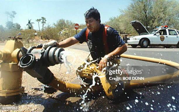 Bruce Claphan of Scottsdale's fire department cools off after fighting a house fire in Phoenix, AZ, 30 July, as temperatures reached 121 degrees...