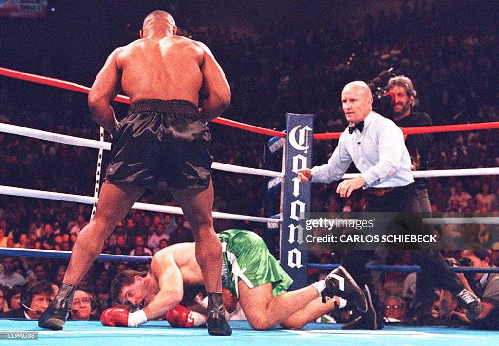 Mike Tyson (L) looks down as Peter McNeeley hits t