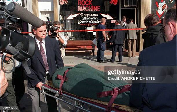 Morgue employees remove the body of a man shot in a motocycle accesssories shop in Montreal's east end 10 Aug with another man wounded in the...