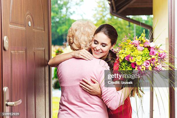 young woman bringing birthday flowers to her grandmother - happy birthday flowers images stock pictures, royalty-free photos & images