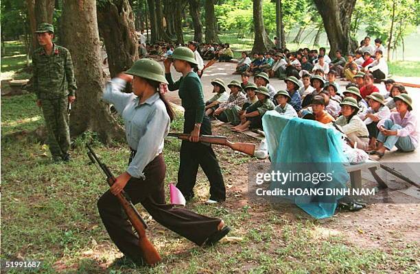 Two women practice throwing grenades as a Vietnamese army officer and their classmates look on a Hanoi botanical park 12 September. Each year high...