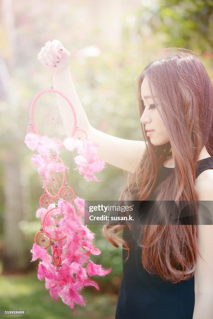 Young woman holding & looking at a dreamcatcher