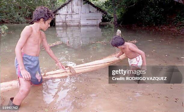 Dos ninos juegan con un tronco de madera 10 Octubre mientras atras se ve su casa completamente cubierta por el agua en el poblado de San Juan del Sur...