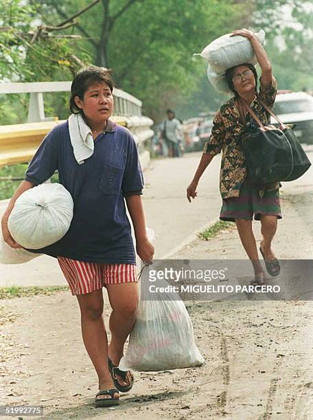 Women carry their belongings as they evacuate Santo Tomas village in the Pampanga Province, located north of Manila, which has been submerged by...