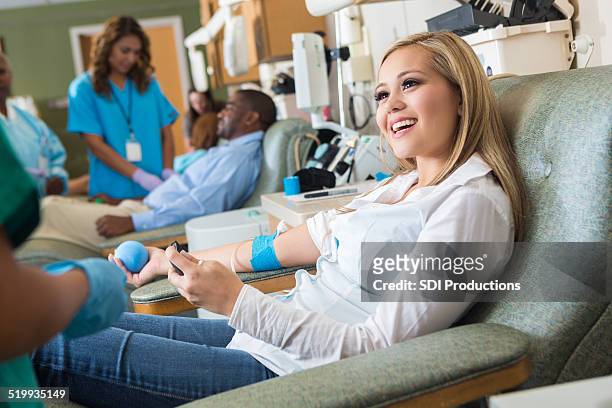 woman donating blood in busy hospital donation bank - blood transfusion stockfoto's en -beelden