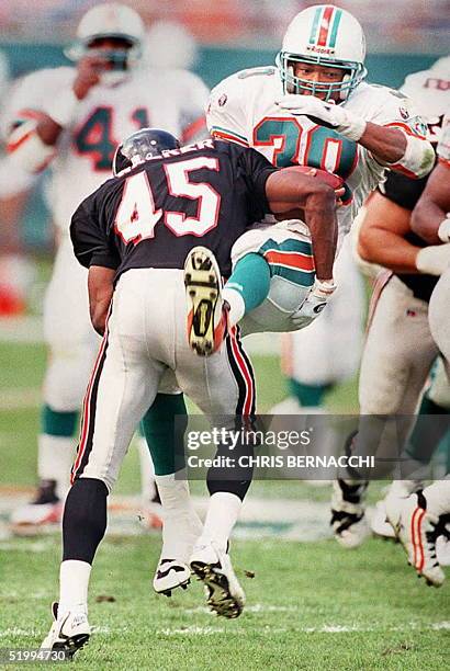 Miami Dolphins running back Bernie Parmalee is upended by Atlanta Falcons cornerback Darnell Walker after Parmalee ran for a short gain in the third...