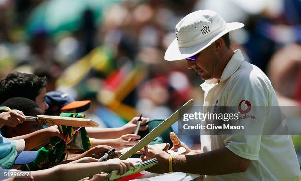 Ashley Giles of England signs autographs and shows a bandaged right thumb during the third day of the fourth test match between South Africa and...