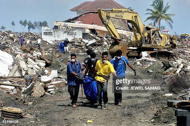 Volunteers carry dead bodies after digging out from the debris of houses in Ule Lhee, outskirts of Banda Aceh, 16 January 2005, three weeks since a...