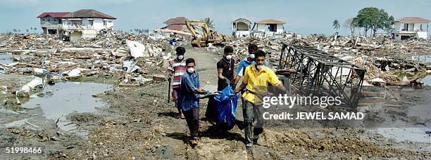 Volunteers carry dead bodies after digging out from the debris of houses in Ule Lhee, outskirts of Banda Aceh, 16 January 2005, three weeks since a...