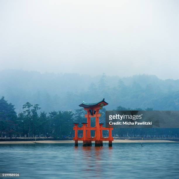 red torii gate at itsukushima shrine on miyajima island in fog - torii gate stock pictures, royalty-free photos & images