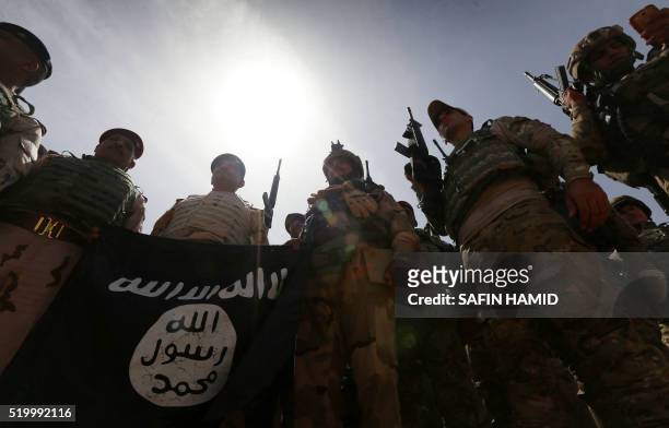Iraqi soldiers hold a flag that they seized from the Islamic State group as they hold a position near the frontline on April 9, 2016 in the town of...