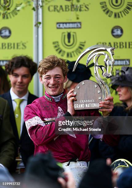 David Mullins poses with the winner's trophy in the Winners' Enclosure after riding Rule The World to victory in the 2016 Crabbie's Grand National at...