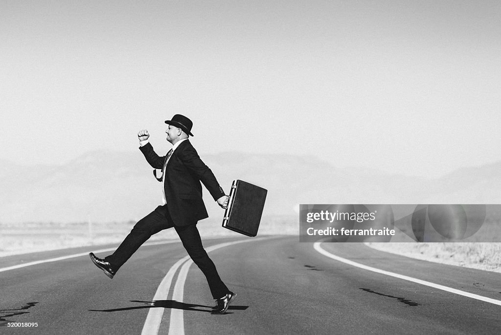 Hopeful businessman with suitcase crossing the road