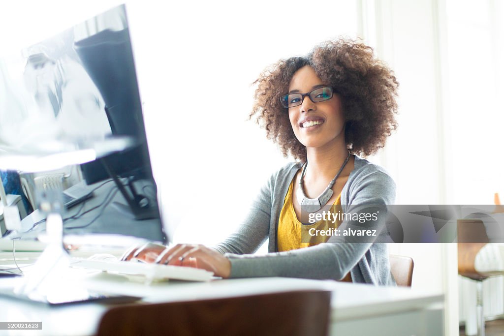 Happy young trainee working on computer