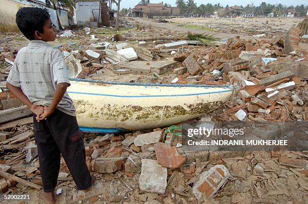 Sri Lankan child stands next to his destroyed house near the devastated beach front in Kalmunai in the Ampara district some 370 kms east of Colombo...