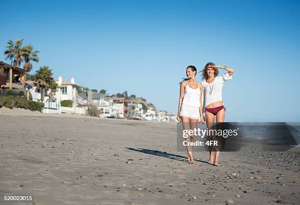 women walking down malibu beach, california - malibu beach stockfoto's en -beelden