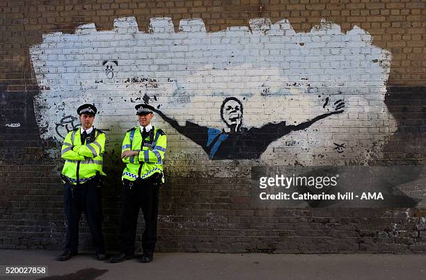 Police officers stand next to a graffiti art mural of former Millwall player and current manager Neil Harris prior the Sky Bet League One match...