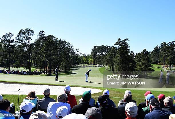 Northern Ireland's Rory McIlroy putts as US golfer Jordan Spieth looks on during Round 3 of the 80th Masters Golf Tournament at the Augusta National...