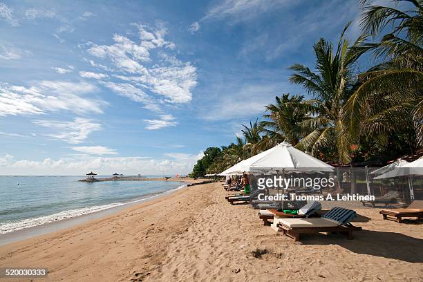 beach chairs and a few people at a beach in bali - sanur stock pictures, royalty-free photos & images