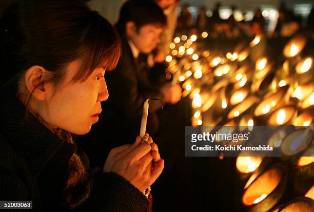 Woman lights a candle to offer a prayer for victims during a memorial service to commemorate the 10th anniversary of the 1995 earthquake in Kobe on...