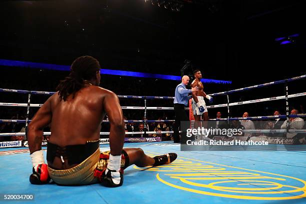 Anthony Joshua of England is ordered back to his corner by the referee as Charles Martin of the United States sits on the canvas during the IBF World...