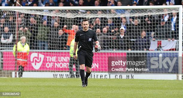 Referee Tony Harrington walks from the pitch holding two bottles that were thrown at Northampton Town goalkeeper Adam Smith prior to Bristol Rovers...