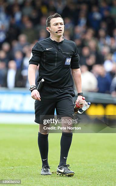 Referee Tony Harrington walks from the pitch holding two bottles that were thrown at Northampton Town goalkeeper Adam Smith prior to Bristol Rovers...