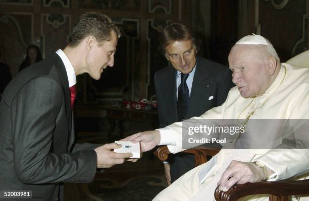 Pope John Paul II gives a gift to the Formula One world champion Michael Schumacher of Germany as Ferrari President Luca Cordero di Montezemolo looks...