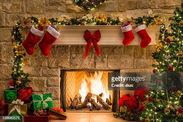christmas fireplace, tree, stockings, fire, hearth, lights, and decorations - kousen stockfoto's en -beelden