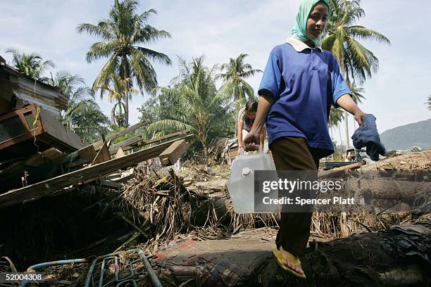 Woman carries water to her home that was damaged in the tsunami January 17, 2005 in Banda Aceh, Indonesia. The province of Aceh, one of the worst hit...
